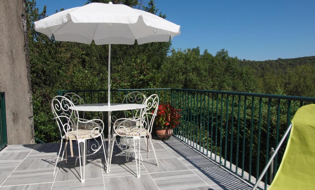 une table et des chaises avec un parasol sur un balcon dans l'établissement L'Espaso, à Gailhan