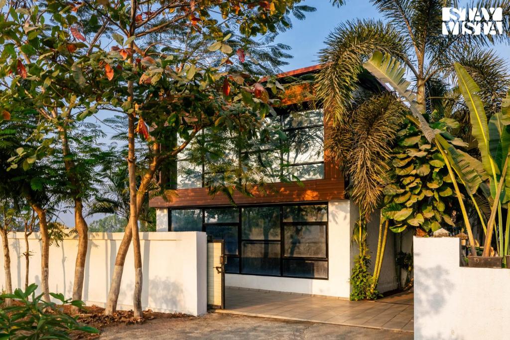 una casa con árboles delante en StayVista's One Villa - Pet-friendly charm with Farm views, Modern decor & A refreshing plunge pool, en Karjat