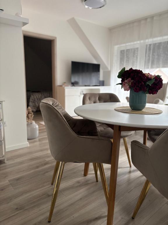 a living room with a table and chairs with a vase of flowers at LaMira 2,3 Apartments in Hajdúszoboszló