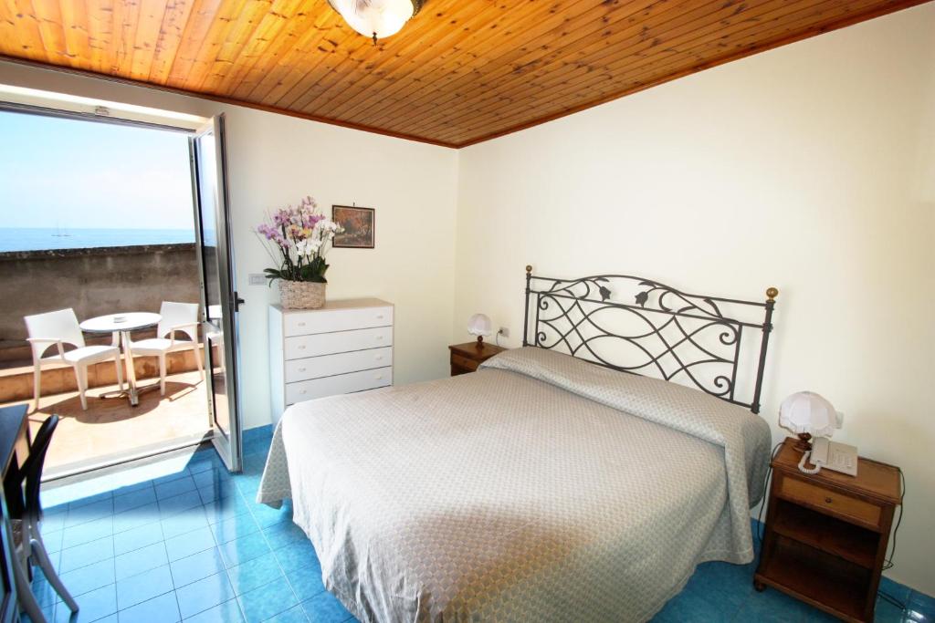 a bedroom with a bed and a table and a balcony at Hotel La Certosa in Massa Lubrense