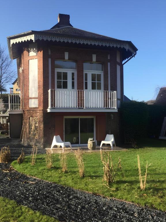 une maison avec deux chaises blanches devant dans l'établissement Gîte 3 personnes Fécamp-Etretat, à Ganzeville