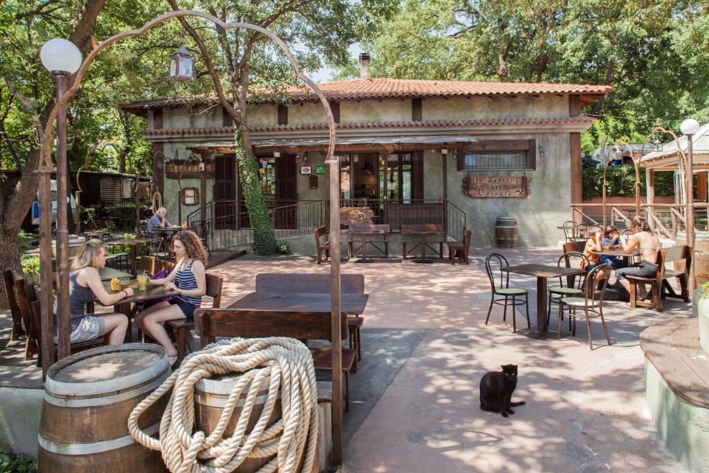 un groupe de personnes assises dans un restaurant avec un chat noir dans l'établissement Caravelle Camping Village, à Ceriale