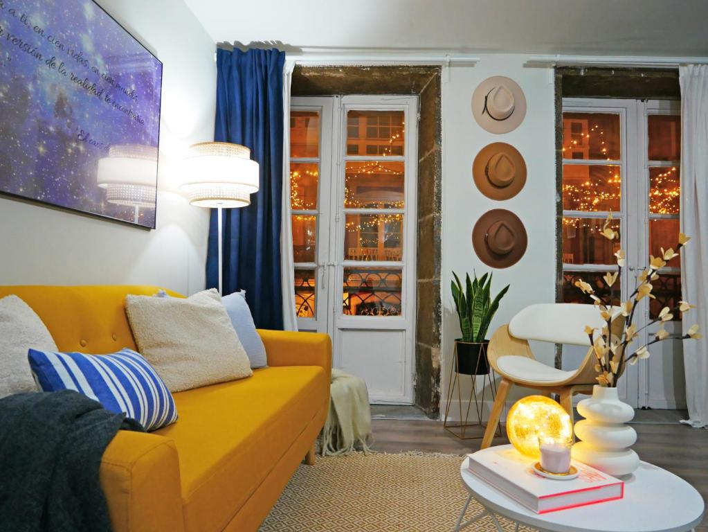 a living room with a yellow couch and a table at Vivienda pleno corazón de la ciudad, As rías in A Coruña