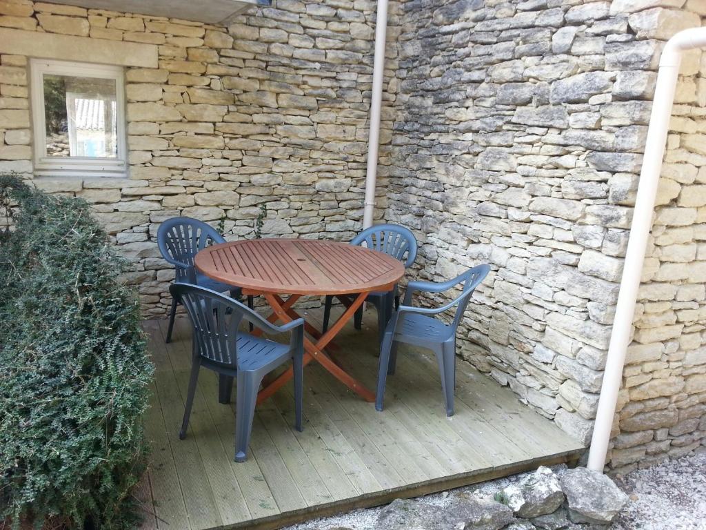 Una mesa y sillas de madera en un patio. en Gordes Le Bastidon, en Gordes