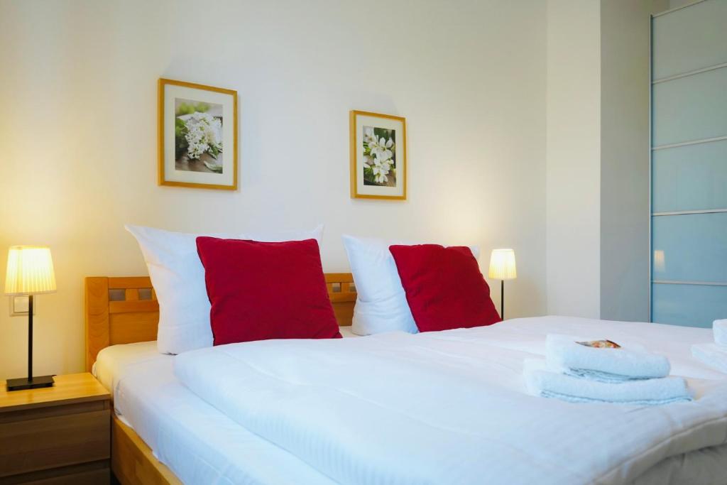 una camera da letto con un grande letto bianco con cuscini rossi di Wohnensemble mit 3 separaten Bereichen- 2 Küchen- 3 Badezimmer- 10 Personen- Garten- Parkplatz a Wolfsburg