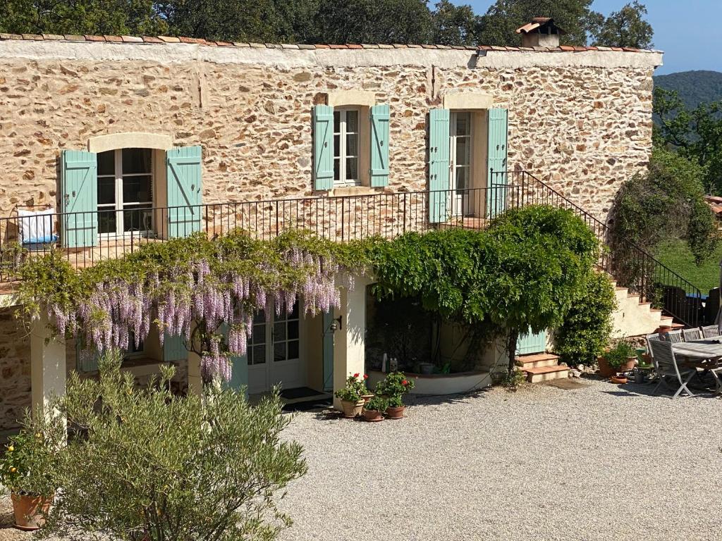 une maison en pierre avec un balcon et des fleurs violettes dans l'établissement La Bergerie, à La Garde-Freinet