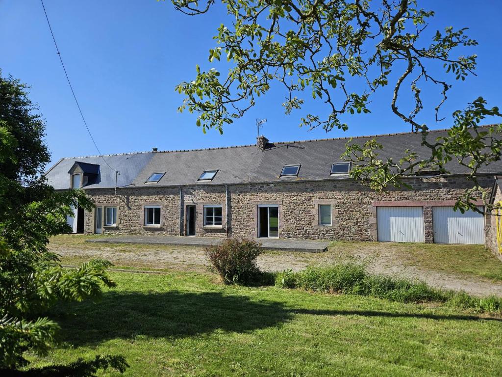 une grande maison en briques avec une cour d'herbe dans l'établissement Jolie Longère Bretonne, à Fréhel