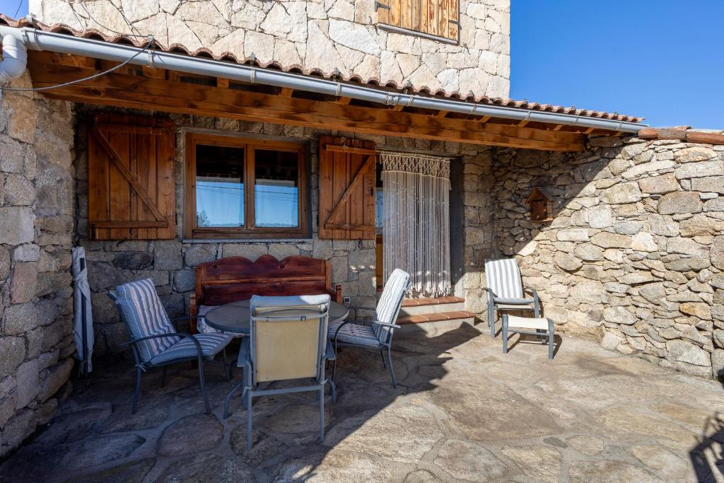 un patio con tavolo e sedie in un edificio in pietra di Casa del Tio Primitivo a Navarredonda de Gredos