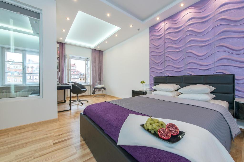 Un dormitorio con una cama con una pared de acento púrpura en Old Town Square P&O Apartments, en Varsovia
