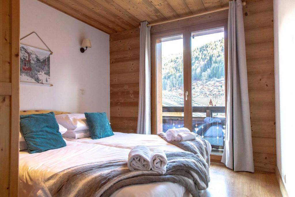 Un dormitorio con dos camas y una gran ventana. en Apartment Morzine Central - Mountain Voyages, en Morzine