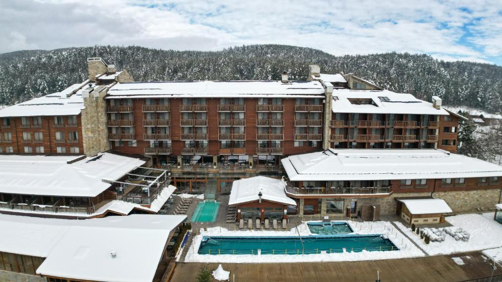 een groot gebouw met besneeuwde daken en een zwembad bij Katarino SPA Hotel in Bansko