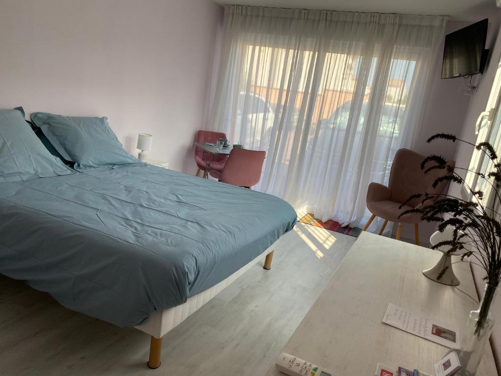 a bedroom with a bed with blue sheets and a window at Chambre d'hôtes chez Marie Pierre in Nissan-lez-Enserune