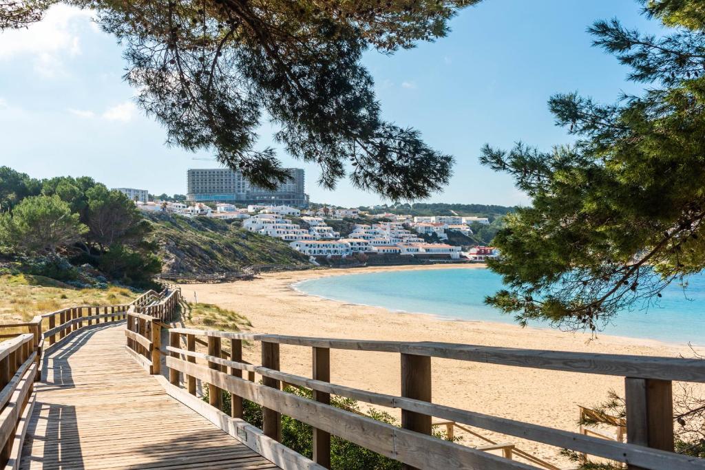 a boardwalk on a beach with a city in the background at Apartamento CASTELLSOL 201 by Mauter Villas in Arenal d'en Castell