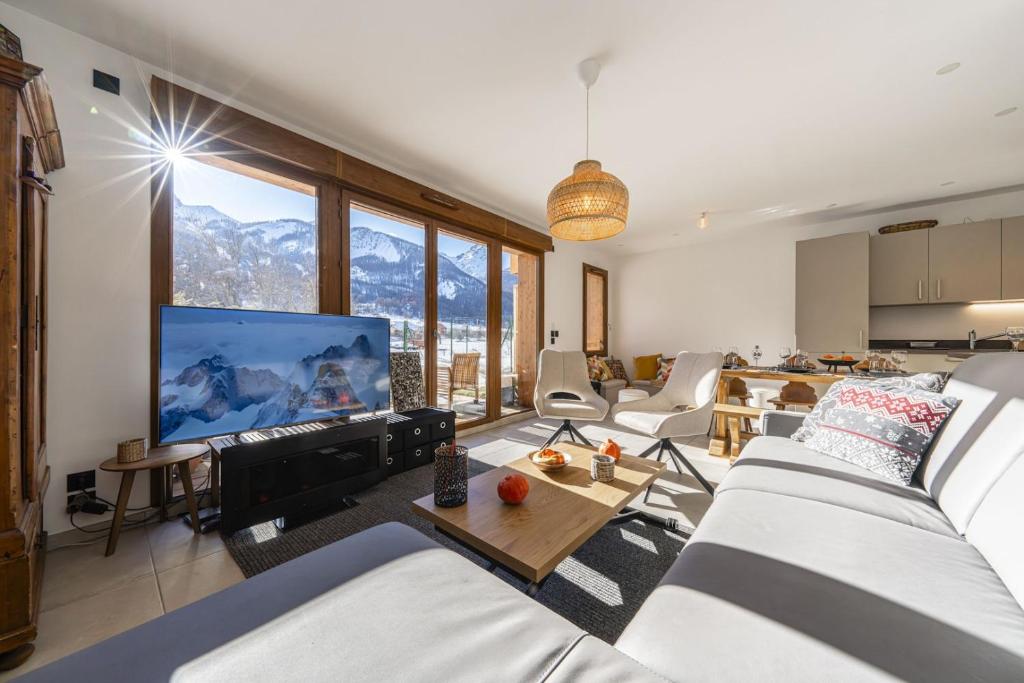 - un salon avec canapés et télévision à grand écran dans l'établissement Serre-Chevalier T4 luxe pied pistes, au Monêtier-les-Bains
