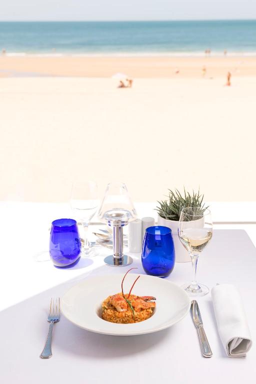 a table with a plate of food on the beach at Hotel Playa Victoria in Cádiz