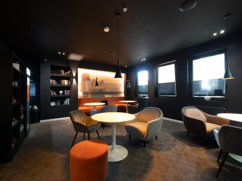 ein Raum mit einem Tisch und Stühlen und Tischen und Fenstern in der Unterkunft JustStay Ratingen Hotel & Apartments in Ratingen