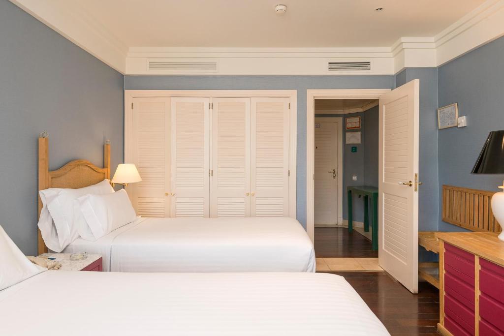 a bedroom with two beds and a closet at Hotel Playa Victoria in Cádiz