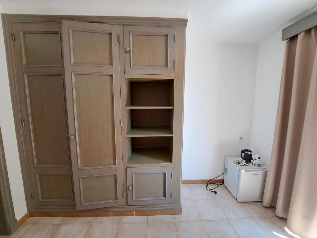 a large wooden cabinet in the corner of a room at Hostal Playa in Cala Santanyi