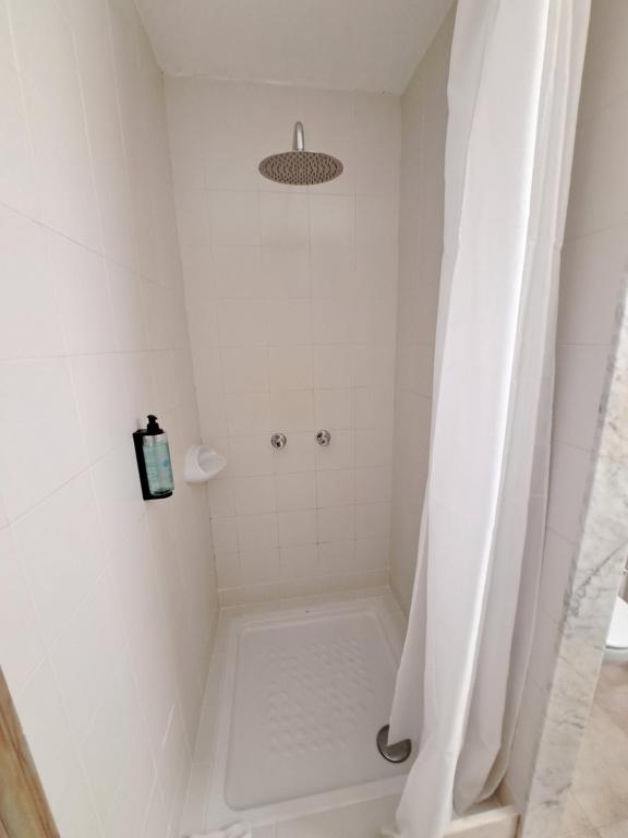 a white shower with a shower curtain in a bathroom at Hostal Playa in Cala Santanyi