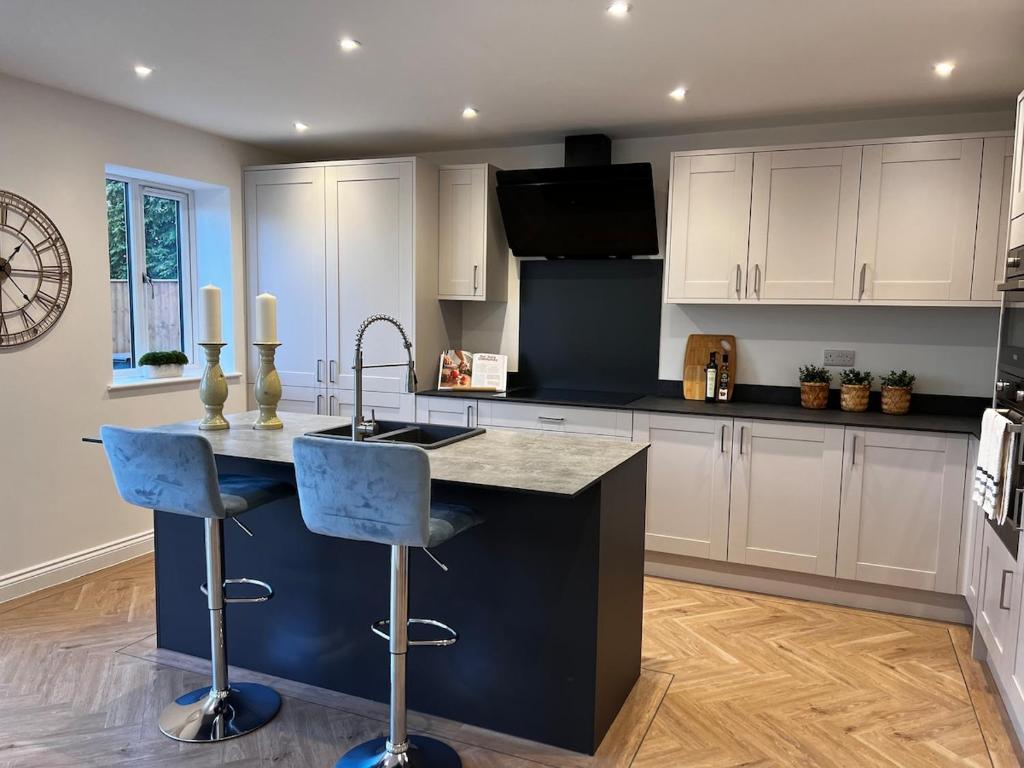 a kitchen with a sink and a counter with stools at Beautiful, luxury house! in Higham on the Hill