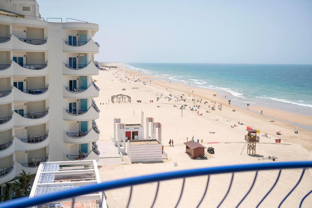 a view of the beach from the balcony of a building at Hotel Playa Victoria in Cádiz