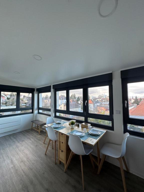 a dining room with a table and chairs and windows at # Le 14 # Nouveau T3 rénové au calme vue sur les Vosges in Riedisheim