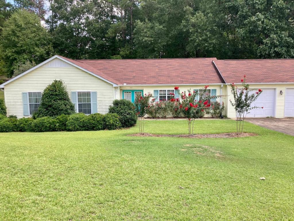 a white house with a red roof and a yard at Rose's House in Lanett