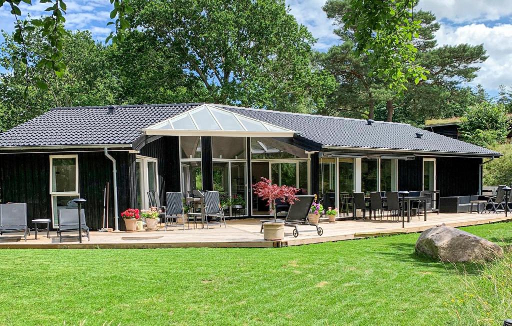 a large black house with chairs and tables in a yard at 5 Bedroom Nice Home In Fårevejle in Fårevejle