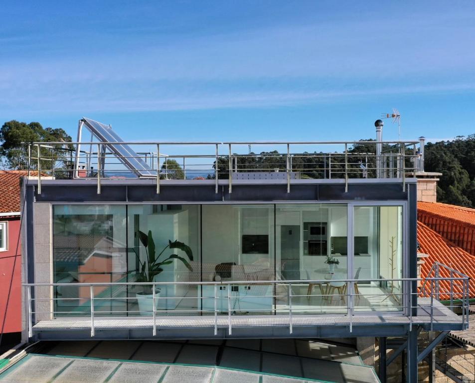a house with a balcony on top of a roof at Apartamento Cubo de Cristal con piscina y vistas al mar in O Grove