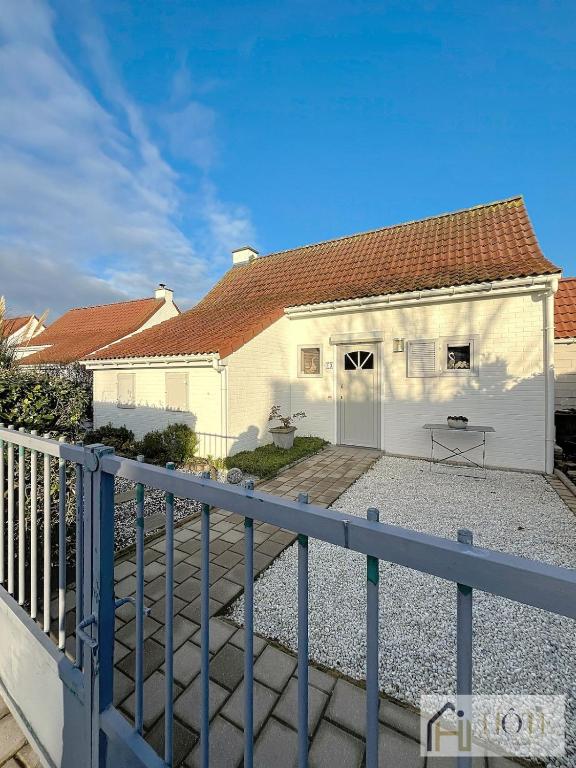 une maison blanche avec une clôture devant dans l'établissement La Belle Vue du Lac - 3 CH, à Ghyvelde