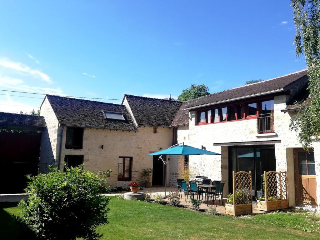 une maison avec une table et un parasol dans la cour dans l'établissement Gîte des Sources-Rumont, à Rumont