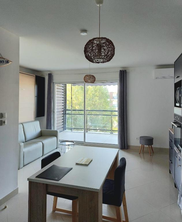 un salon avec une table et un canapé dans l'établissement Grand Studio à 300m de la plage dans Résidence calme - une seule pièce, à Gruissan