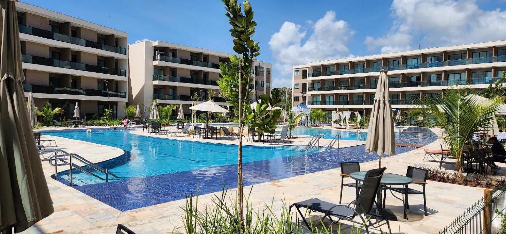 a swimming pool with chairs and tables in a hotel at Malia Beach Experience - Studios em Muro Alto por Yolo in Ipojuca