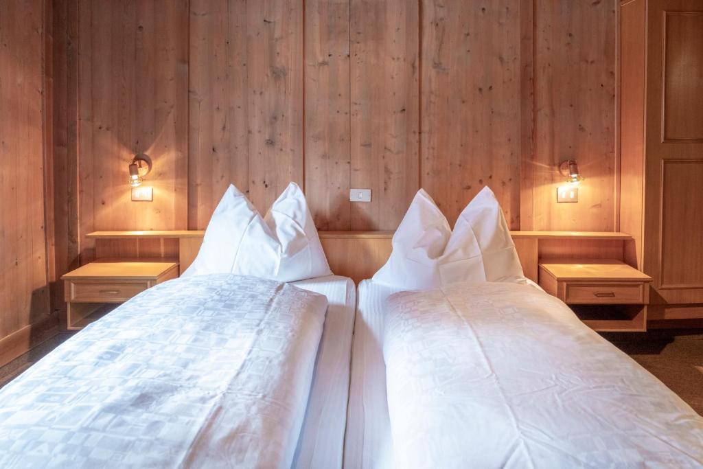 two white beds in a room with wooden walls at B&B Öboluckna in Molini di Tures