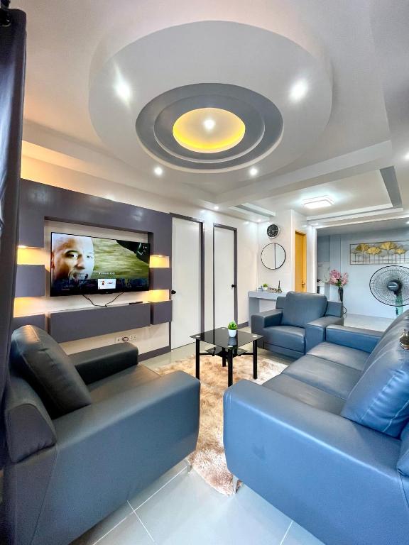 a living room with blue couches and a flat screen tv at MC2 Homestay Butuan in Butuan