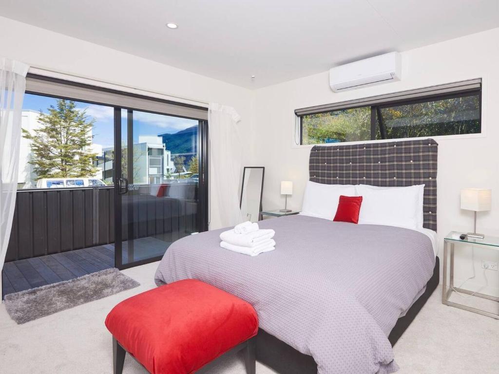 Un dormitorio con una cama grande y un taburete rojo en Central Spa Getaway Studio (F1), en Queenstown