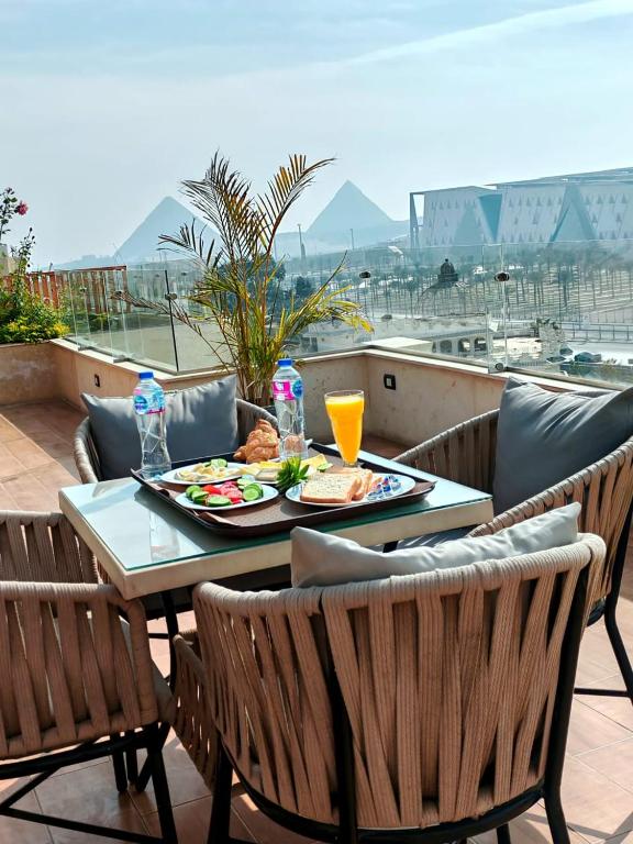 Kush Hotel, Grand Museum & Pyramids View في القاهرة: طاولة مع طبق من الطعام على شرفة