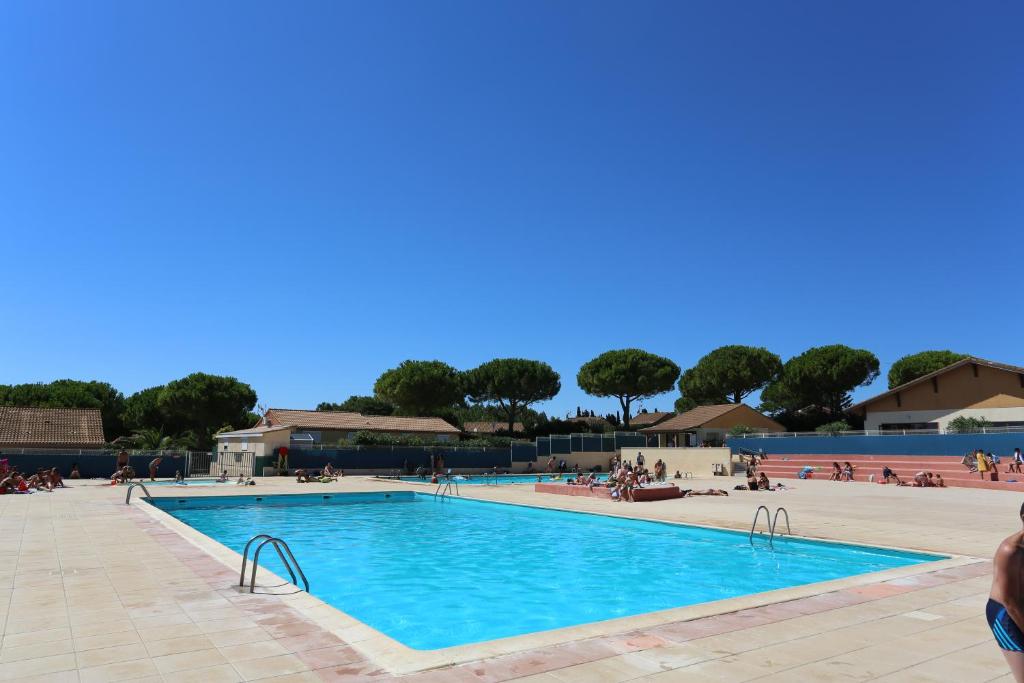 a swimming pool at a resort with people sitting around it at Sun Résidences Horizon Bleu in Vendres