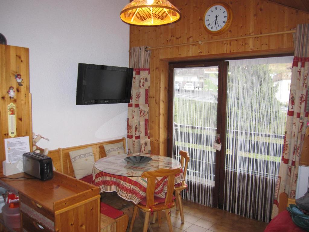 une salle à manger avec une table et une horloge au mur dans l'établissement F2 Grand Confort en face du télécabine, à Thollon-les-Mémises