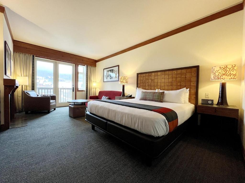 ein Hotelzimmer mit einem großen Bett und einer Couch in der Unterkunft Ski In Ski Out Stowe Studio at Spruce Peak in Stowe