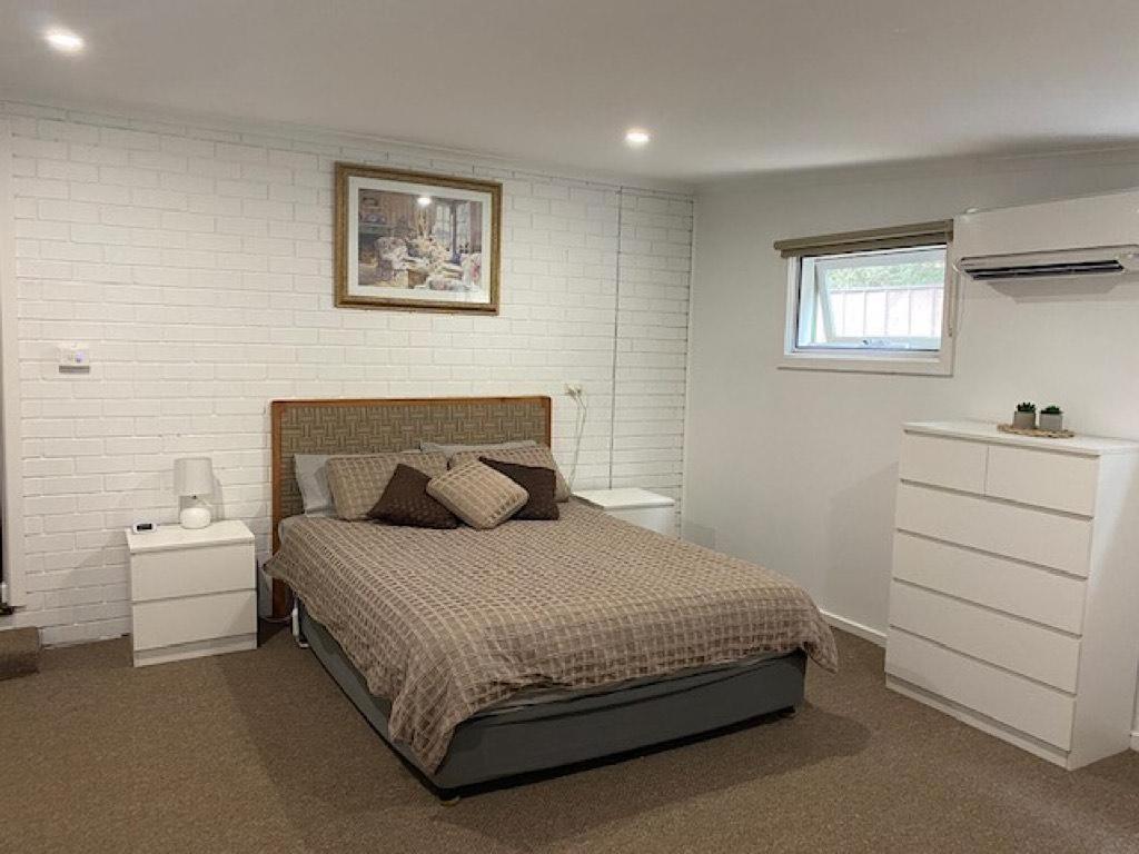 a bedroom with a bed and a white brick wall at The River Rest in Nagambie in Nagambie