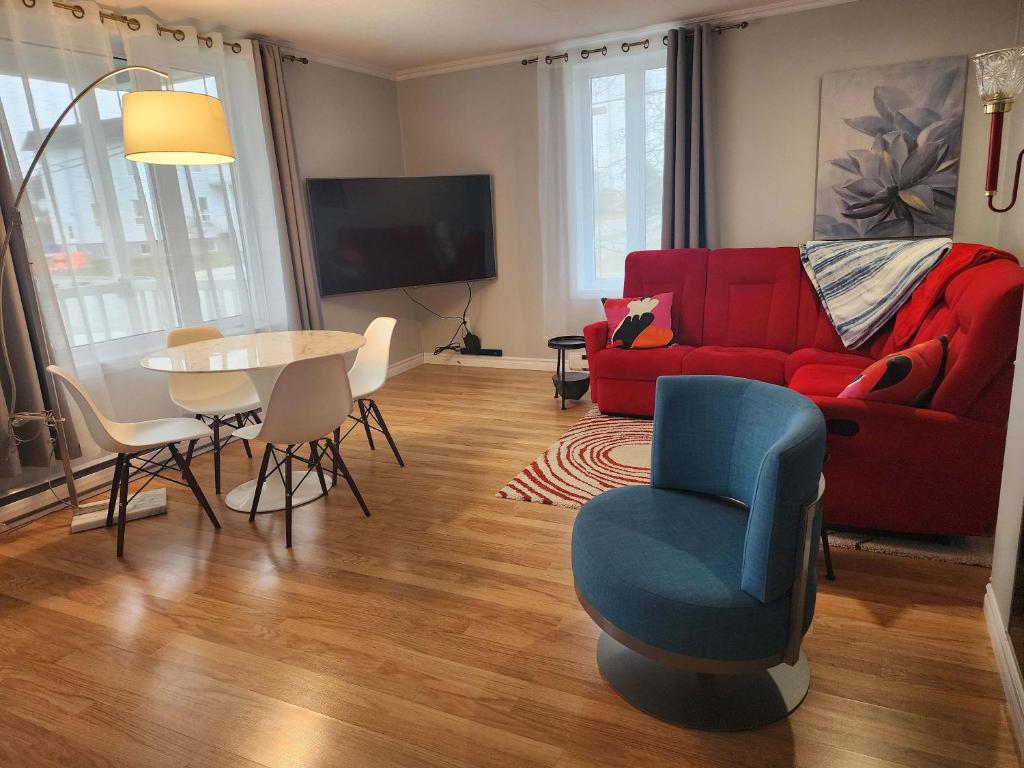 a living room with a red couch and a table and chairs at Maison 3 chambres Inspiration in Amos