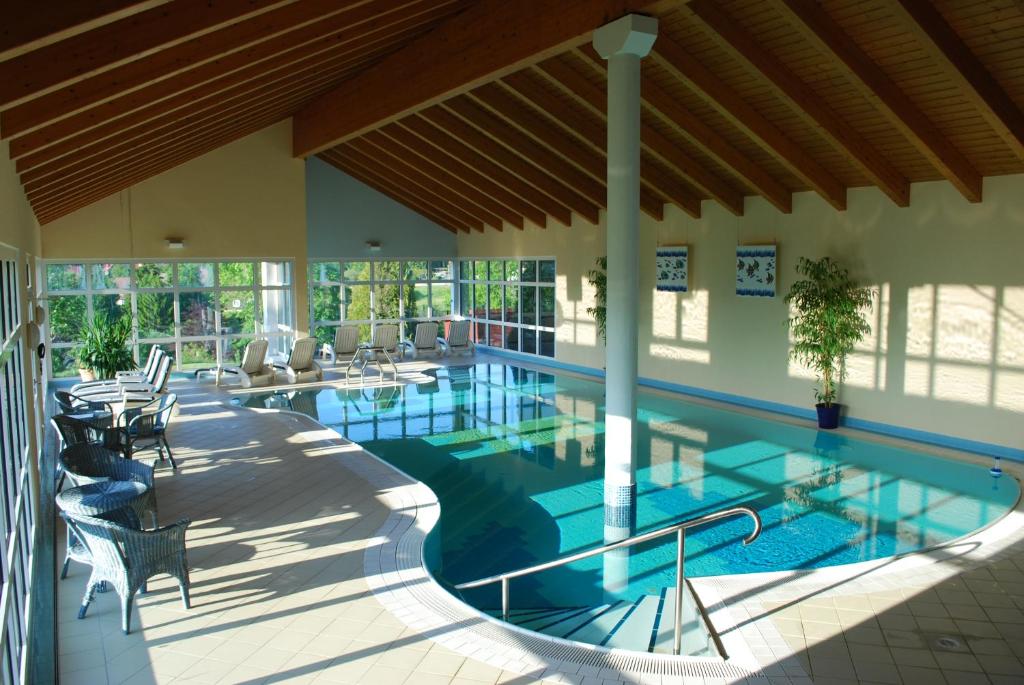 a swimming pool with tables and chairs in a building at Vitalhotel Sonneneck in Hohegeiß