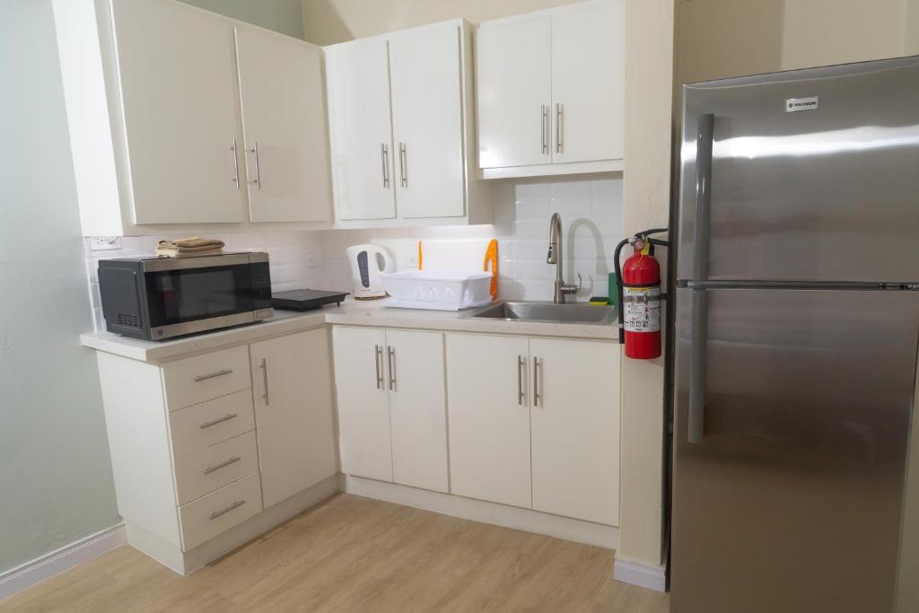 a kitchen with white cabinets and a stainless steel refrigerator at Crown Point Beach Hotel in Crown Point