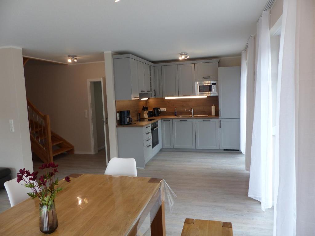 ヴァルスローデにあるFerienhaus Sonnenzauber 1の白いキャビネットと木製のテーブルのあるキッチン