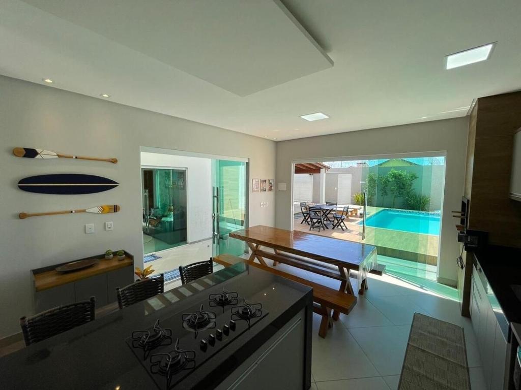 a kitchen with a stove and a table and a pool at Casa Rosa Pestana - min da Praia - PRADO BAHIA in Prado