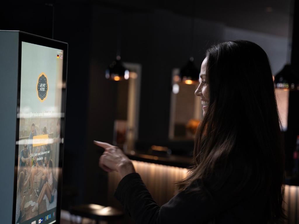 a woman pointing to a screen in a restaurant at JustStay Mülheim Hotel & Apartments in Mülheim an der Ruhr