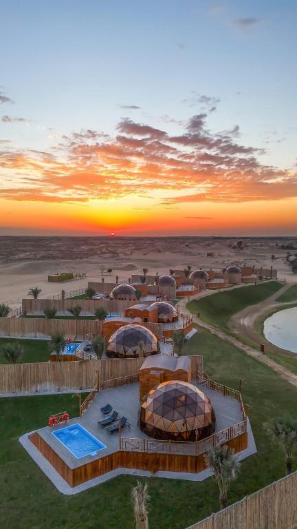 eine Luftansicht eines Resorts mit Sonnenuntergang in der Unterkunft Al Marmoom Oasis Luxury Experiential Desert Domes in Dubai