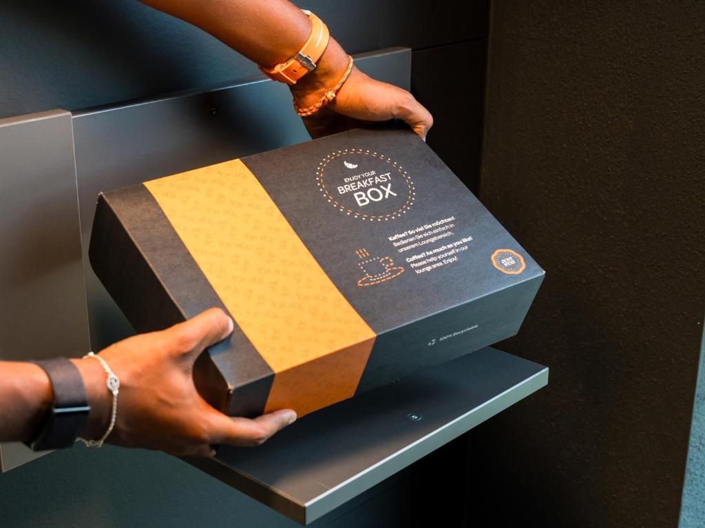 a person holding a box in a refrigerator at JustStay Mülheim Hotel & Apartments in Mülheim an der Ruhr