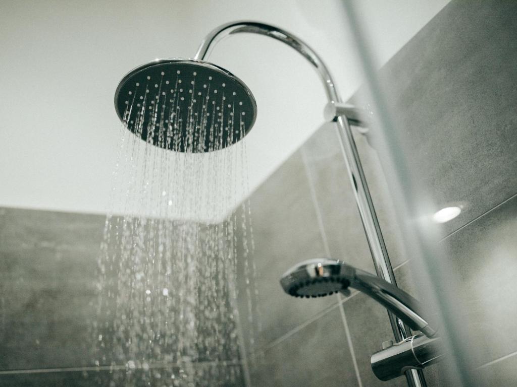 a shower with a shower head in a bathroom at JustStay Mülheim Hotel & Apartments in Mülheim an der Ruhr